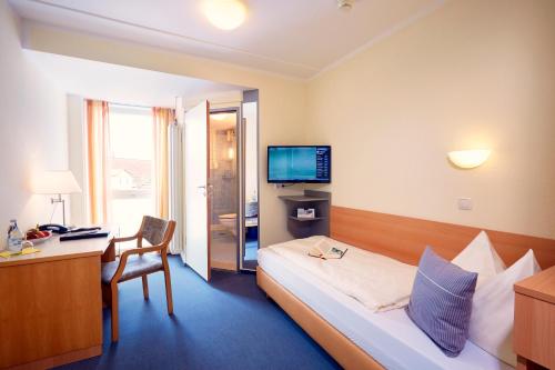 Habitación de hotel con cama, escritorio y TV. en IN VIA Hotel en Paderborn