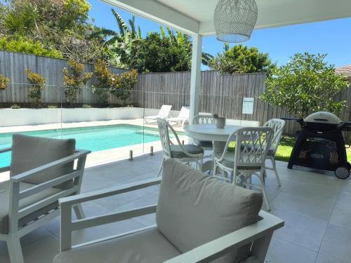 a patio with a table and chairs and a pool at Tranquil Whitehaven Retreat in Mooloolaba in Mooloolaba