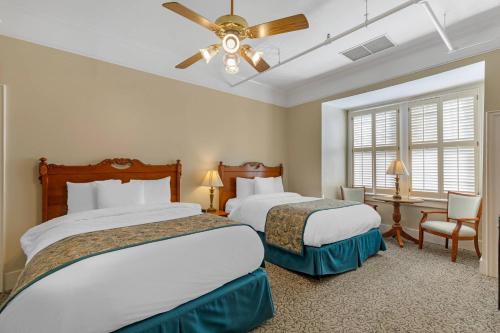 a hotel room with two beds and a ceiling fan at Windsor Hotel, an Ascend Collection Hotel in Americus