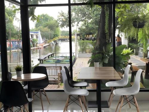 a group of tables and chairs in front of a window at Rimnam Hotel Suk Sawat 70 in Ban Khru Nok