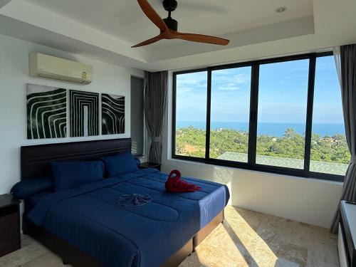 a bedroom with a blue bed with a large window at Sea view Villa Josefina - 3 bedroom in Nathon Bay