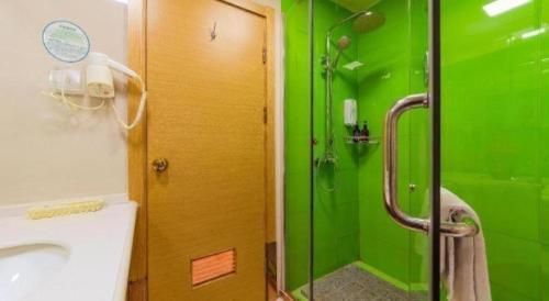 a green bathroom with a sink and a shower at GreenTree Inn Tangshan Xueyuan Road Business Hotel in Fujiatun