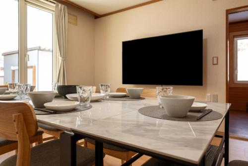 una sala da pranzo con un grande tavolo con una televisione di 緑の夢の家 a Furano