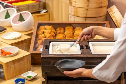 a person holding a spatula and a frying pan at Grand Lectore Yugawara - TKP Hotels & Resorts in Yugawara