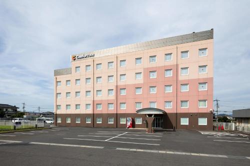 a large pink building with a parking lot at Comfort Inn Zentsuji Inter in Marugame