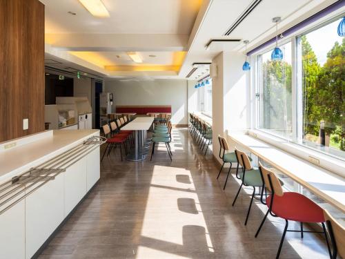 a cafeteria with tables and chairs and windows at Comfort Inn Zentsuji Inter in Marugame