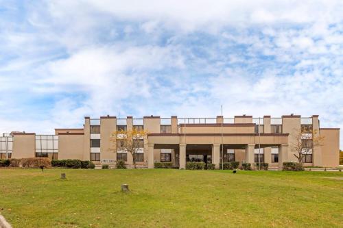 a large building with a grass field in front of it at Clarion Hotel & Conference Center Lansing West in Lansing