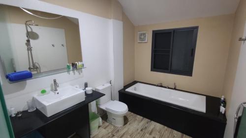 a bathroom with a tub and a toilet and a sink at Villa Whitney in Lamai