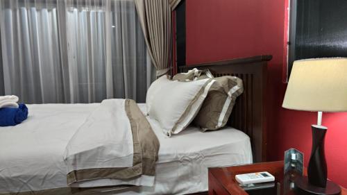 a bedroom with a bed and a table with a lamp at Villa Whitney in Lamai