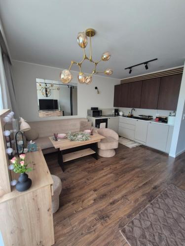 Una sala de estar con una mesa y una cocina. en Apartament Leśny Zakątek, en Reda