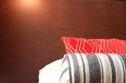a bed with a red and white pillow and a wall at Home Hotel Temperance in Malmö
