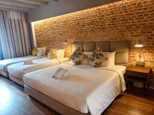 two beds in a room with a brick wall at Loke Thye Kee Heritage Hotel, Georgetown Penang in George Town