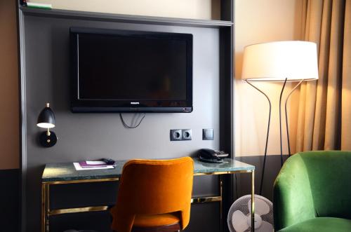a room with a chair and a television on a wall at Home Hotel Temperance in Malmö
