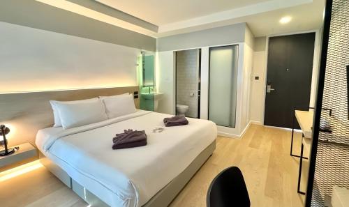 a bedroom with a large white bed and a bathroom at ISTY Design Hotel in Chiang Mai