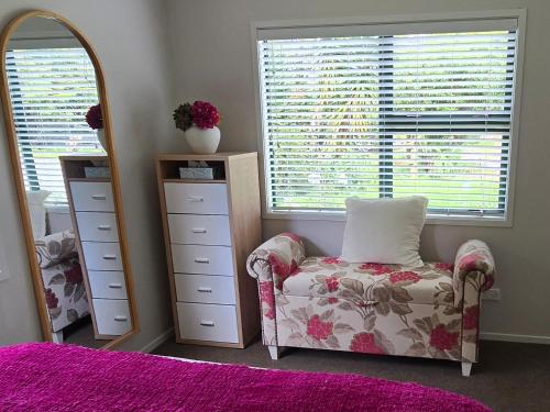 a bedroom with a dresser and a chair and a mirror at Chestnut Bay Country Retreat in Whakamarama