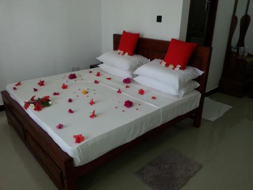 Una cama con almohadas rojas y flores. en Villa River View en Aluthgama