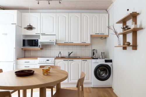a kitchen with white cabinets and a wooden table at Stylish & Cozy 1BR Apt in Historical Neighborhood in Tampere