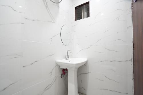 a white bathroom with a sink and a brick wall at CITY CHARM Home Stay in Dehradun