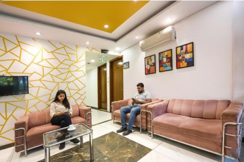 Due persone sedute sui divani in una sala d'attesa di Via Under Bridge - Near Nizamuddin Railway Station a Nuova Delhi