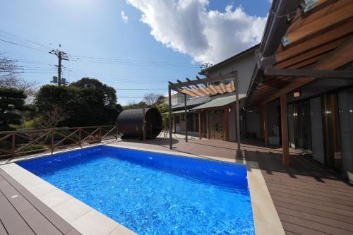 a swimming pool on a deck next to a house at パーパスリゾート EG Sky terrace 熱川 in Higashiizu