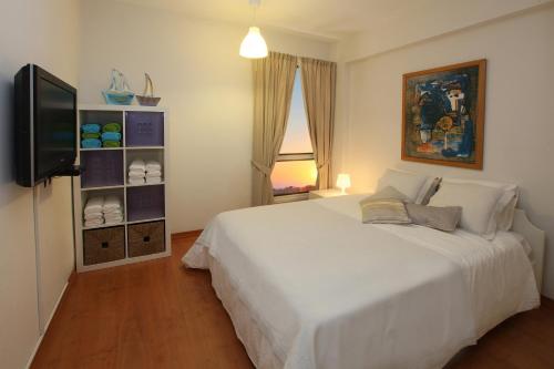 Mackenzie Beachfront Suite في Scala: غرفة نوم بسرير أبيض وتلفزيون