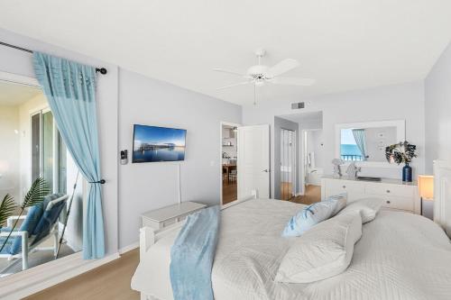 a white bedroom with a bed with blue pillows at Ocean Oaks PHB-8 in Cape Canaveral