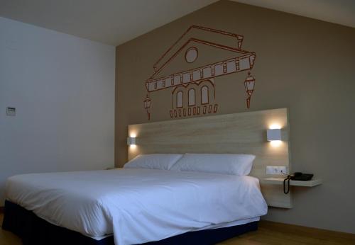 a bedroom with a large white bed with a building on the wall at Hotel Balneario de Graena in Graena