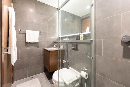 a bathroom with a toilet and a glass shower at Luxury 1BR Apartment - Pool View - The Crest Dubai in Dubai