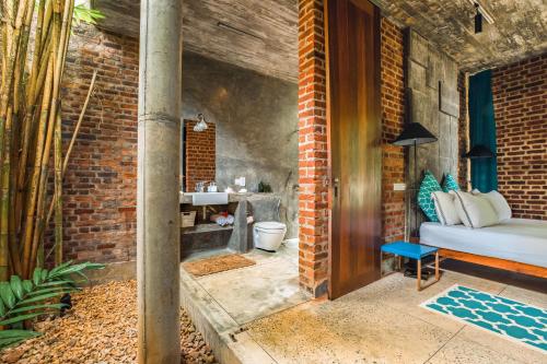 Un baño con paredes de ladrillo con una cama y un inodoro. en Walatta House, en Tangalle