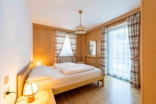 a bedroom with a bed and a large window at Cesa Vivi in Canazei