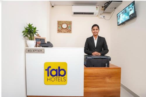 Un hombre de pie en un mostrador de recepción en una oficina. en FabHotel Paramhans Guest House - Sant Ravidas Ghat, en Varanasi