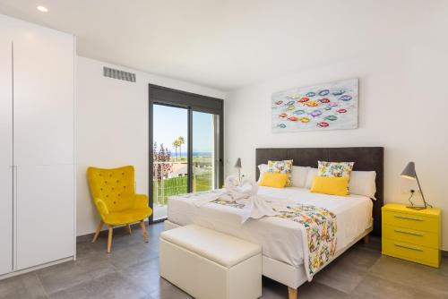 a bedroom with a bed and a yellow chair at Villa Dolce Vita in Son Bou