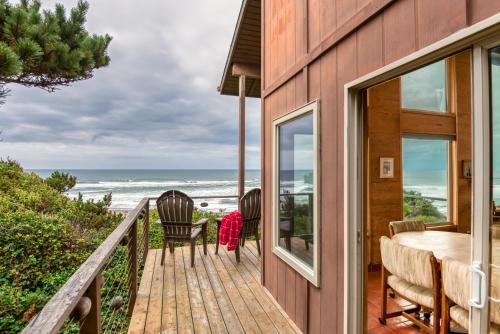 a house with a wooden balcony with a table and chairs at RidgeTop in Lincoln City