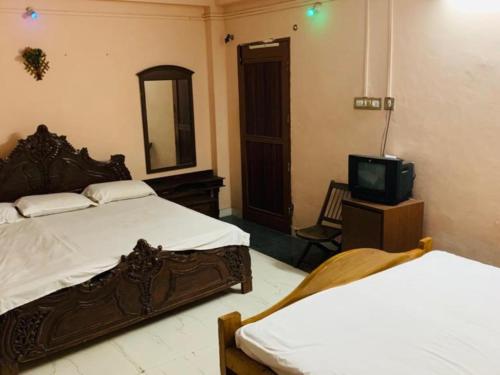 a bedroom with two beds and a tv in it at JS Homestay in Nāgercoil
