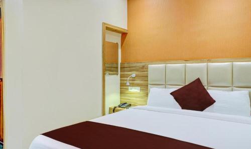 a bedroom with a large white bed with a brown headboard at Hotel Amber Sun City in Mumbai