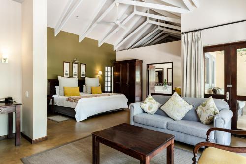 um quarto com uma cama e um sofá em uma sala em Perry's Bridge Hollow Boutique Hotel em Hazyview