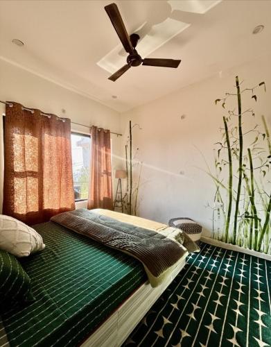 a bedroom with a green bed with a ceiling fan at The Little Idyll in Dharmsala