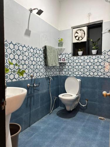 a blue and white bathroom with a toilet and a sink at The Little Idyll in Dharmsala