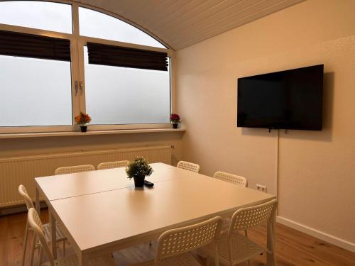 T&K Apartments - Comfortable 4 and 5 room Apartments - 20min Fair Messe CGN في أوفرات: غرفة طعام مع طاولة مع كراسي وتلفزيون بشاشة مسطحة