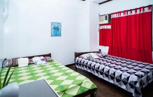 Del CarmenMangrove Breeze Country Inn by RedDoorz的一间卧室设有两张床和红色窗帘