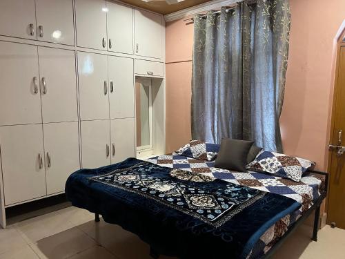 Schlafzimmer mit einem Bett mit Fenster und weißen Schränken in der Unterkunft Baithak homestay in Lucknow