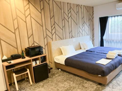 a bedroom with a bed and a desk with a television at ホテルリブマックス那覇波の上2 in Naha