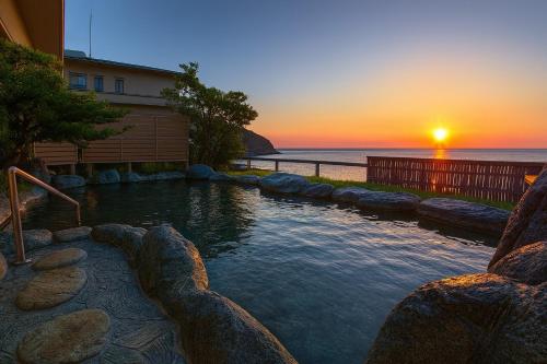 a swimming pool with a sunset in the background at Atagawakan in Higashiizu