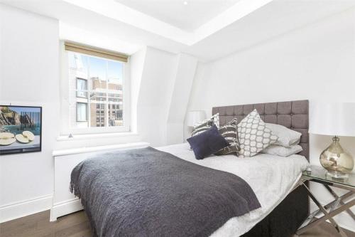 a white bedroom with a bed and a window at Prime West End The Covent Garden Design Flat in London