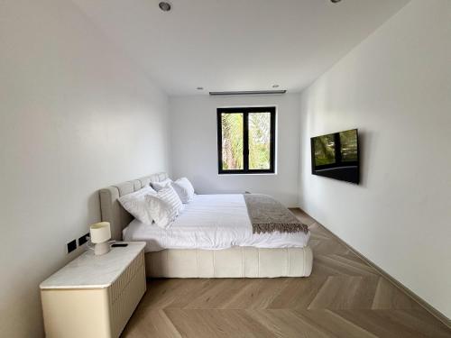 a white bedroom with a bed and a window at Luxe & Privacy Orchard Villas Pasak 4BR in Laguna Phuket