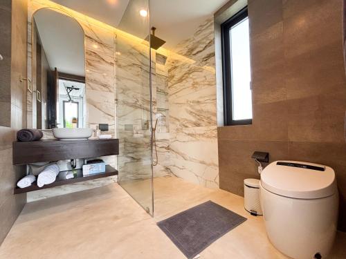 a bathroom with a toilet and a glass shower at Luxe & Privacy Orchard Villas Pasak 4BR in Laguna Phuket