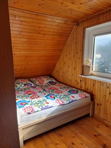 a bed in a wooden room with a window at Borowy Las wita Was in Borowy Las