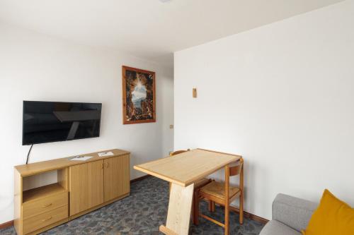 a living room with a table and a tv at Dolomitihouse FRASSEN in Fiera di Primiero