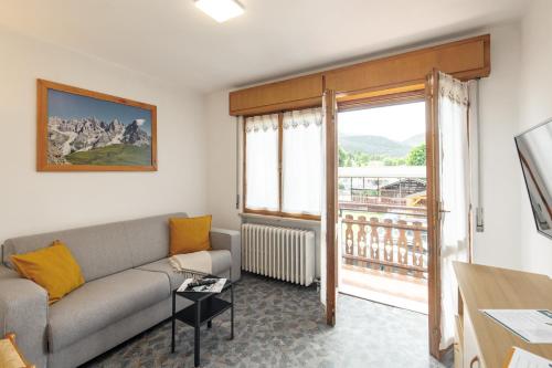 a living room with a couch and a large window at Dolomitihouse FRASSEN in Fiera di Primiero