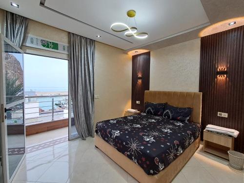 Un dormitorio con una cama y un balcón. en Appartements meublés à louer à Jebha avec une charmante vue sur la mer, en Yebha